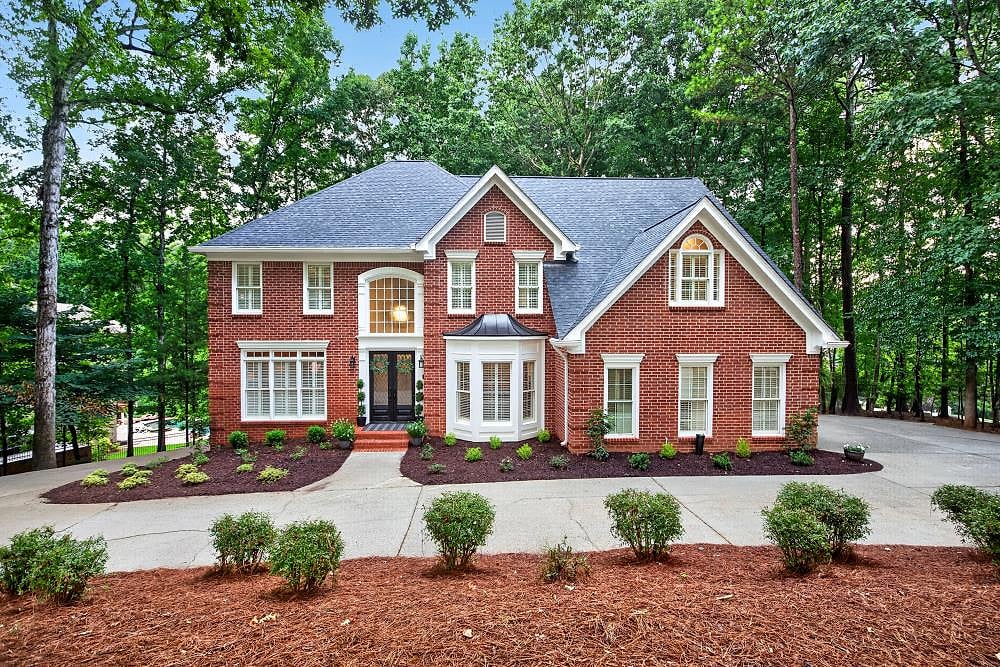 A red brick two-storey home with a freshly cleaned driveway by KM Property Restorations